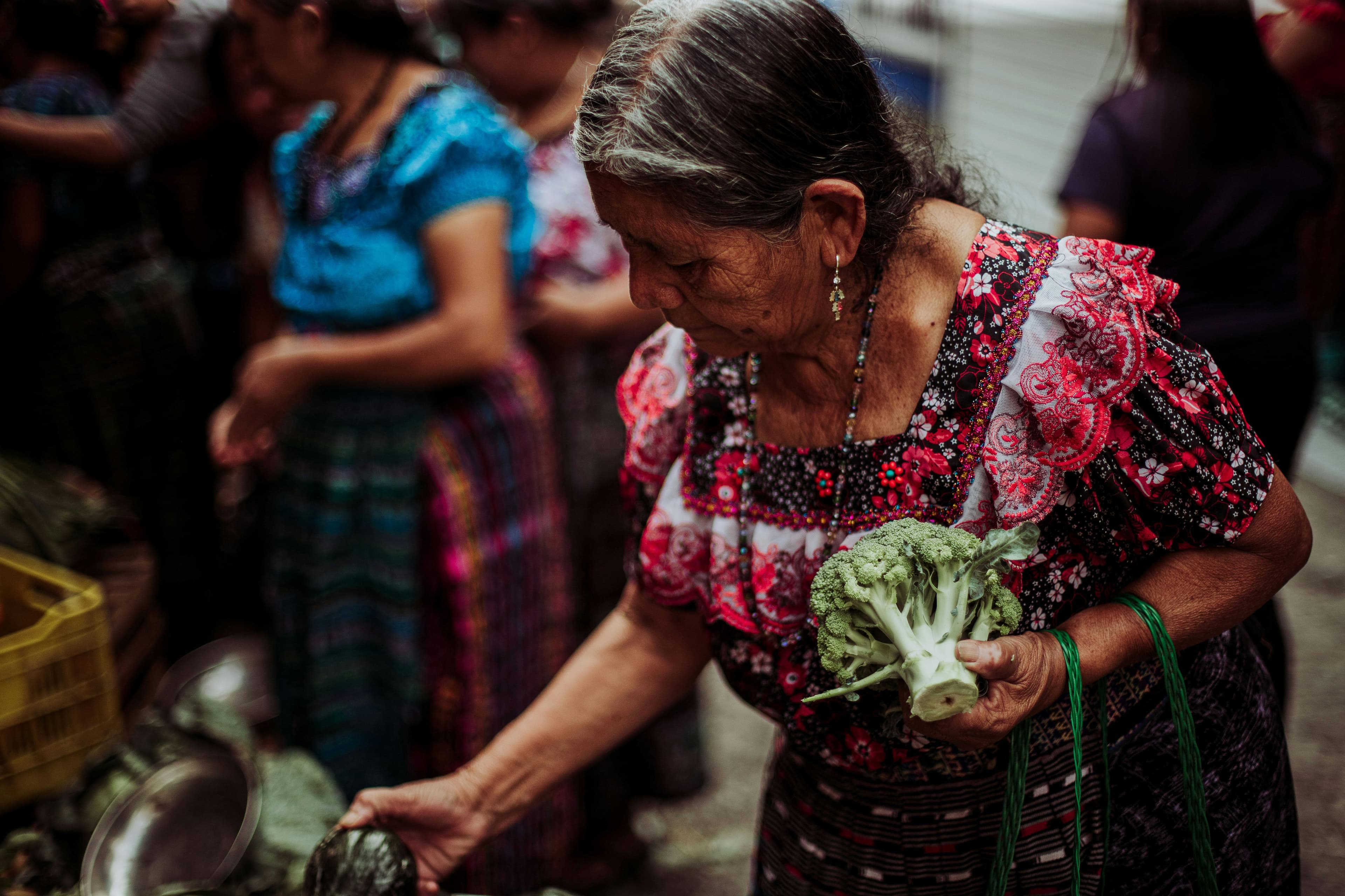 An older woman smiling warmly from behind her stall at a local market.
